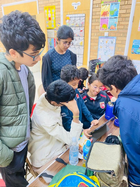 Group of junior A3C members gathered around a tablet at a club session, working through chess together